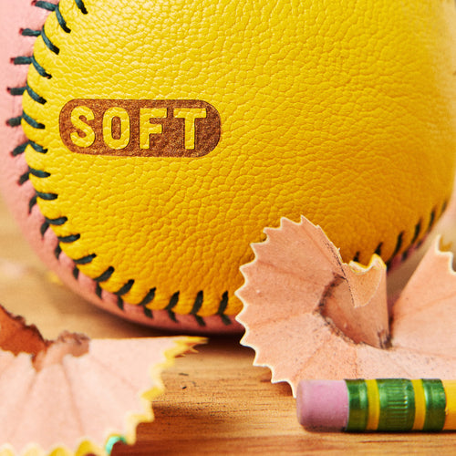 Close-up of the word soft burned into yellow leather, next to pencil shavings and a pink eraser