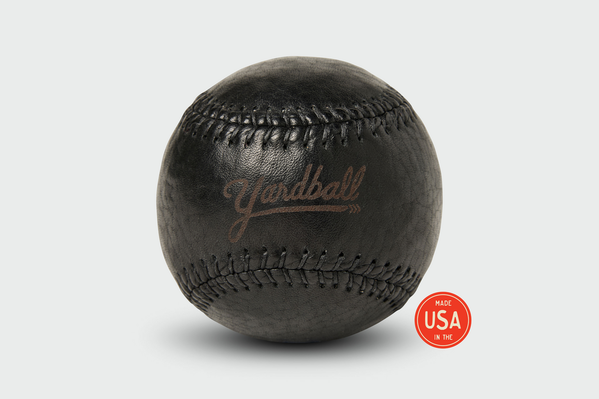 Black Yardball angled view showing full leather grain texture and natural stitching - yard game toss ball